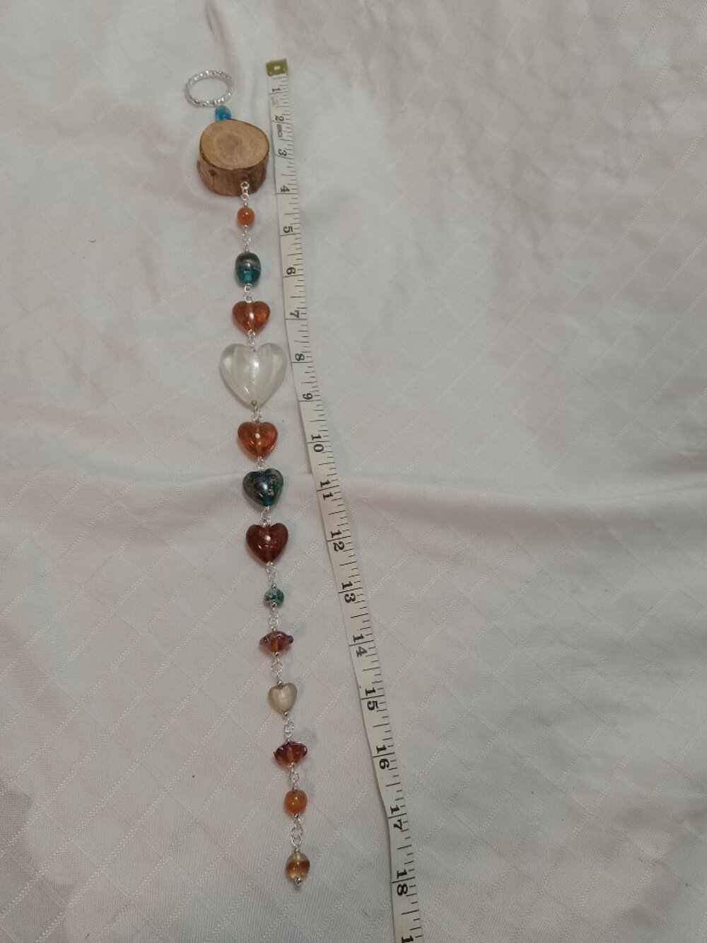 Handmade hanging decoration featuring handcrafted glass beads on a wooden base